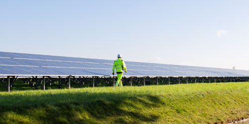 Man walking next to a solar panel